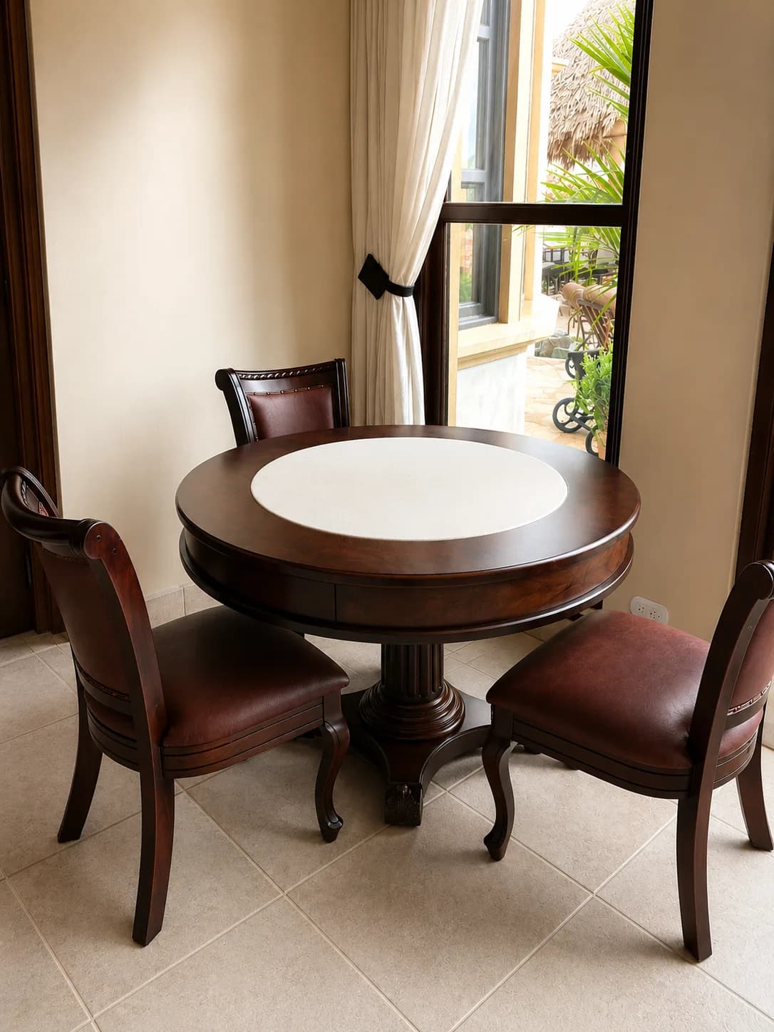 Round dining table with four matching chairs beside a window